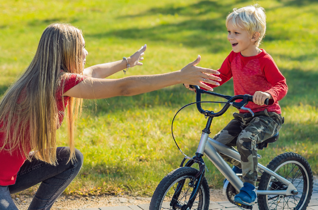 Caregiver supporting a child learning to ride a bike